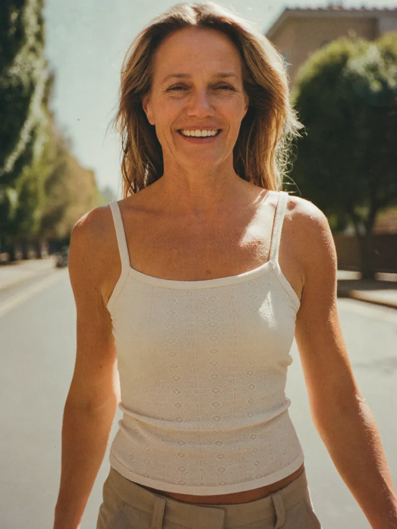 Una mujer camina sonriendo por una calle arbolada